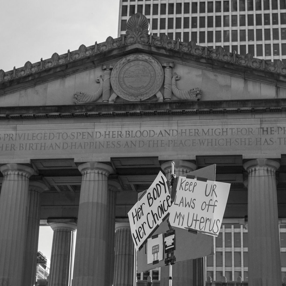 Protesters wave signs reading "Her Body Her Choice" and "Keep Ur Laws off My Uterus" at Legislative Plaza